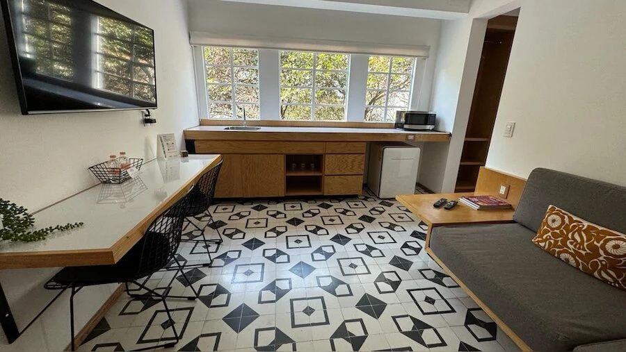 Geräumige Suite mit gemustertem Fliesenboden, Sitzbereich und großer Fensterfront.