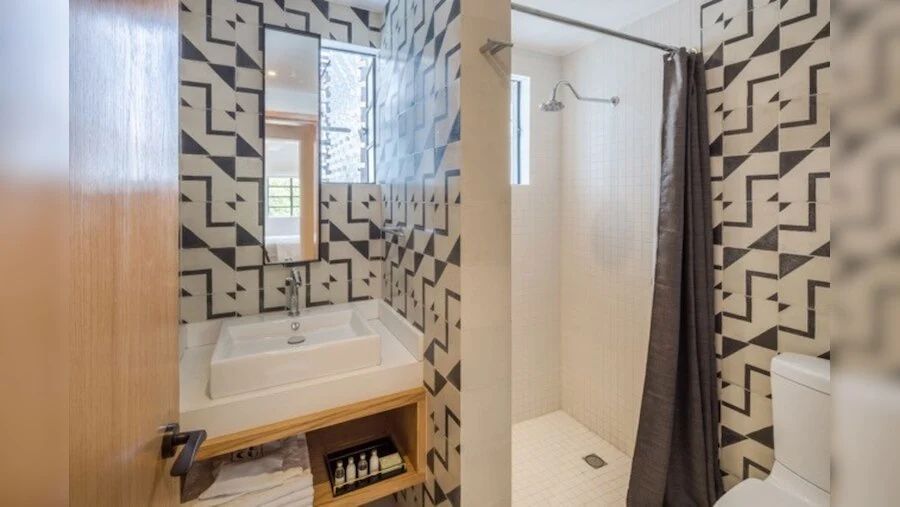 Badezimmer mit gemusterten Fliesen, weißem Waschbecken und separatem Duschbereich.