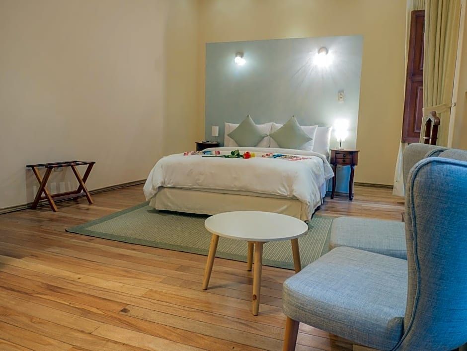 Doppelbett mit weißer Bettwäsche, Sitzbereich und Holzboden im Hotelzimmer.