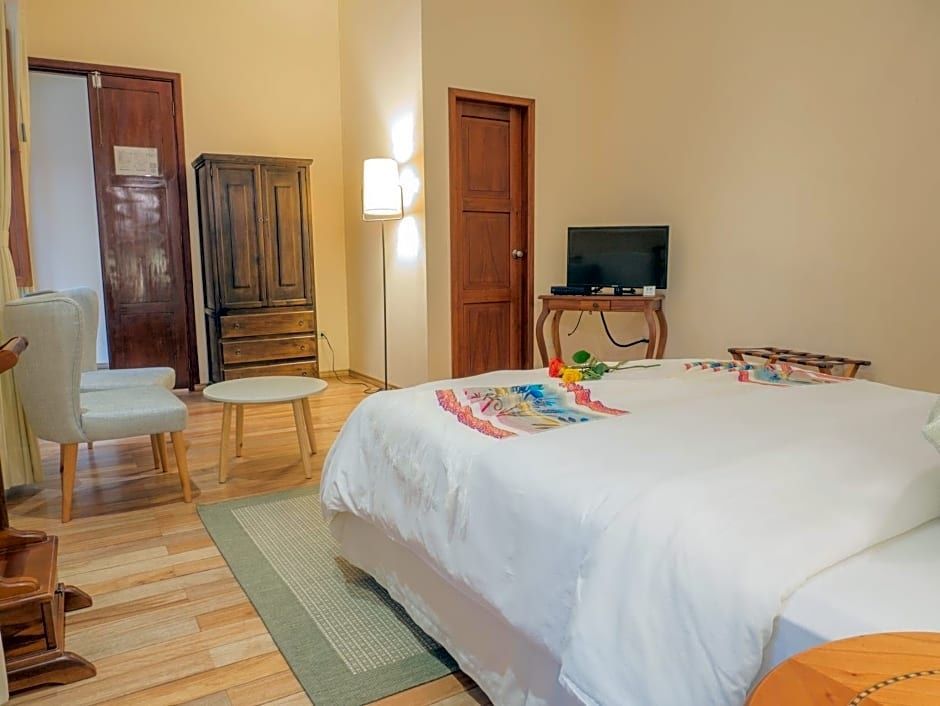 Geräumiges Hotelzimmer mit Doppelbett, antikem Holzschrank und Fernseher.