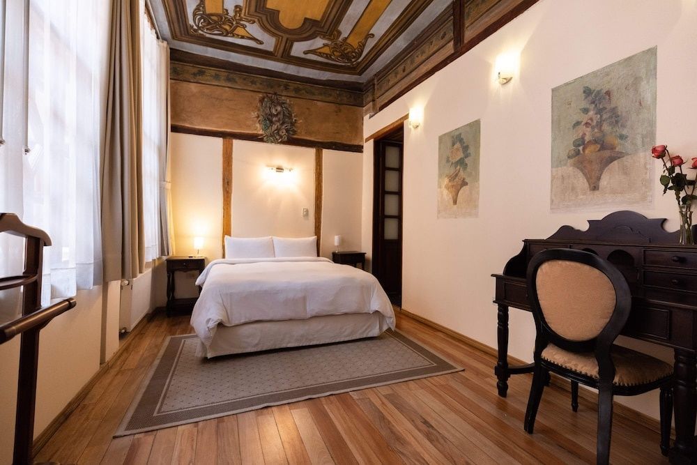 Gästezimmer mit aufwendig bemalter Decke, Parkettboden und einem kleinen Schreibtisch.