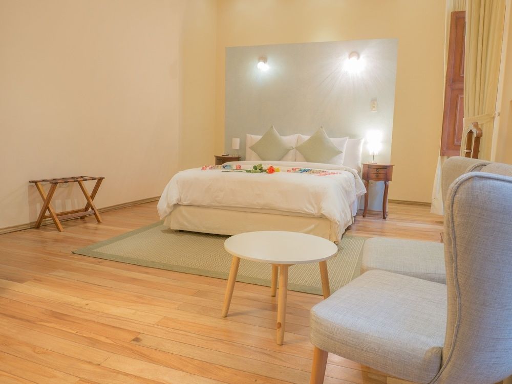 Hell gestaltetes Schlafzimmer mit Parkettboden, weißem Doppelbett und Couchtisch.