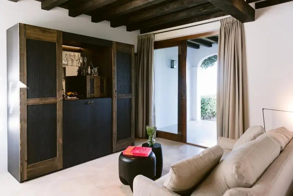 Sitzbereich im Zimmer mit schwarzem Schrank, Sofa und Blick auf die Terrasse.