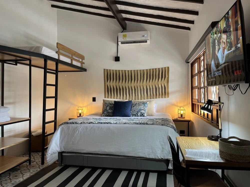 Schlafzimmer mit Doppelbett, Hochbett, Schreibtisch und Holzdekoration an der Wand.