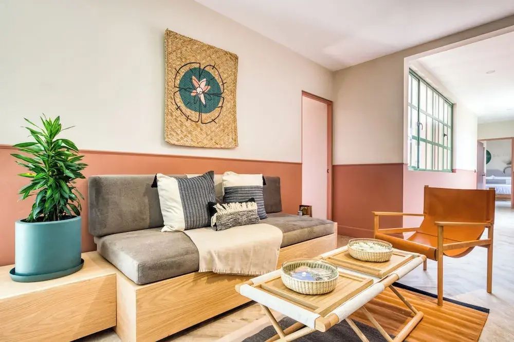 Wohnbereich mit gepolstertem Sofa, Holztisch und Wanddekoration an der Wand.