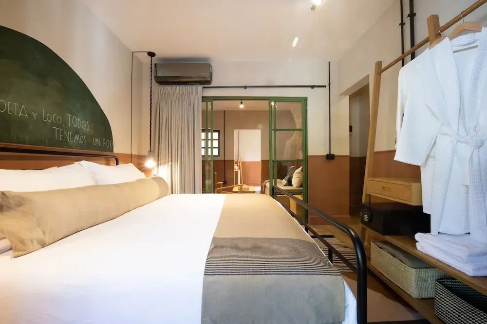 Schlafzimmer mit weißem Doppelbett und einer grünen Glasschiebetür im Raum.