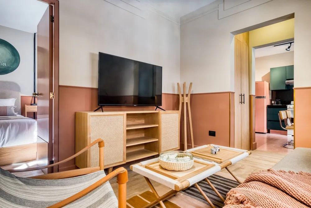 Flachbildfernseher auf einer Holzkommode neben Beistelltischen im Wohnraum.
