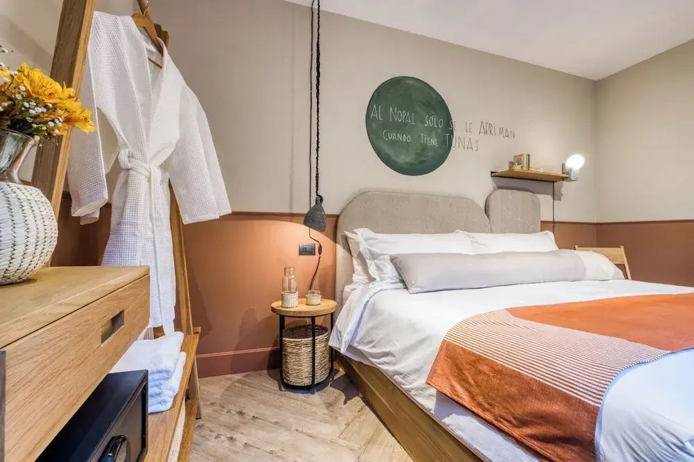 Schlafzimmer mit Doppelbett, hölzernem Nachttisch, Kleiderständer und weißem Bademantel.