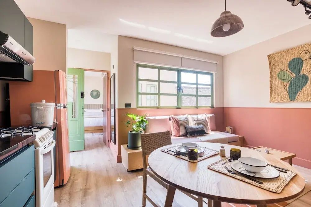 Wohnbereich mit rundem Esstisch, Sitzbank am Fenster und Blick ins Schlafzimmer.