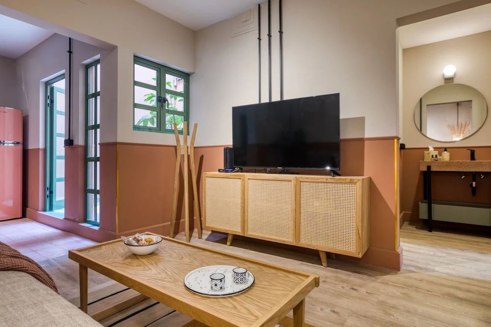 Wohnbereich mit Fernseher auf einem Holzsideboard und niedrigem Couchtisch.