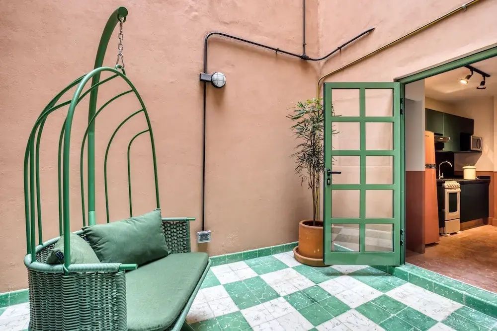Grüner Hängesessel auf einer Terrasse mit grünem und weißem Fliesenboden.
