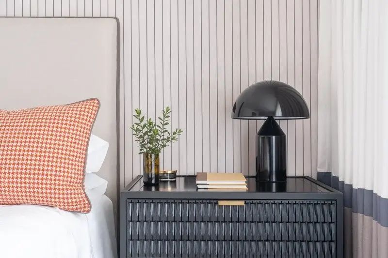 Schwarzer Nachttisch mit schwarzer Tischlampe, Notizbüchern und Pflanze im Hotelzimmer.