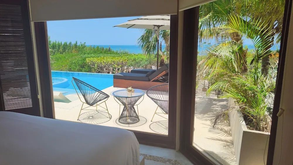 Terrasse mit Sitzgelegenheiten, einem Pool und Blick auf das Meer unter blauem Himmel.