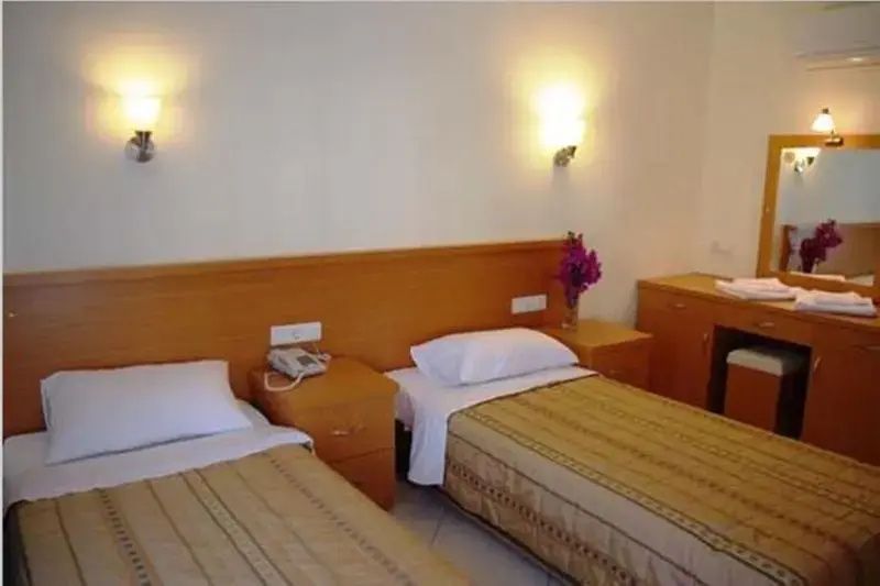 Schlafzimmer mit zwei Einzelbetten, Holz-Kopfteil und Wandleuchten.