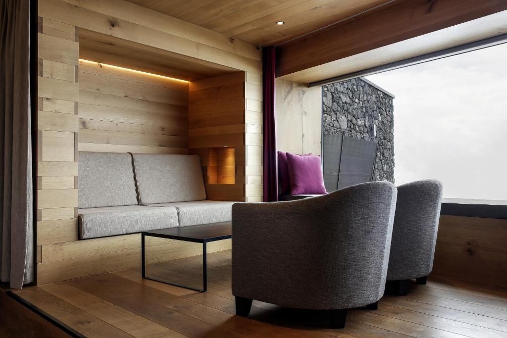 Sitzbereich im Zimmer mit Holznische, grauem Sofa, zwei Sesseln und schwarzem Couchtisch.
