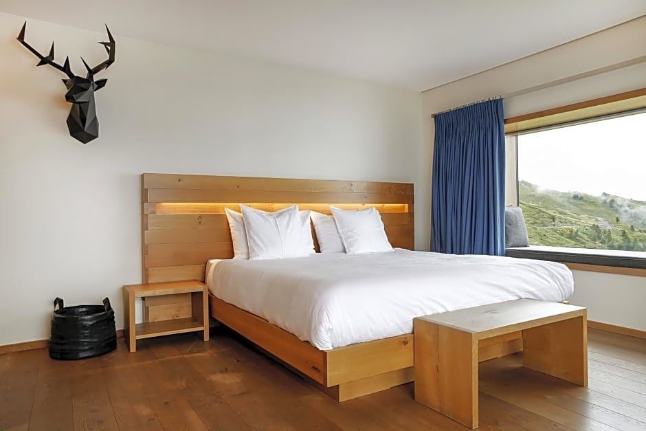 Doppelbett aus hellem Holz mit weißer Bettwäsche und beleuchtetem Kopfteil.