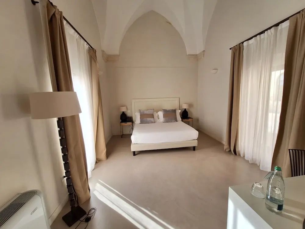 Helles Hotelzimmer mit einem Doppelbett unter einer hohen gewölbten Decke.