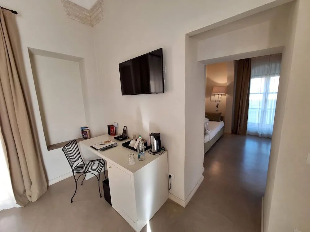 Schreibtisch mit Stuhl und Fernseher an der Wand neben dem Raumdurchgang.