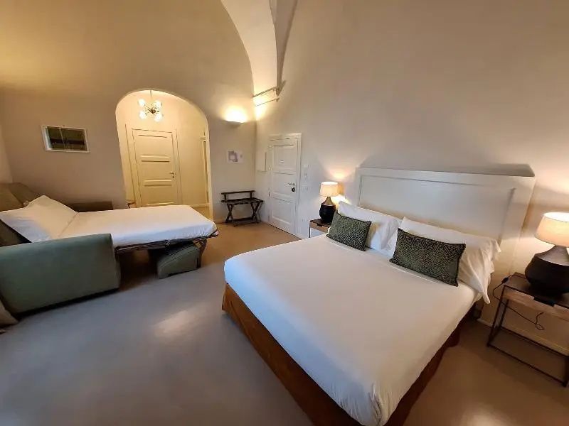 Geräumiges Zimmer unter einem Gewölbe mit Doppelbett und zweitem Schlafbereich.