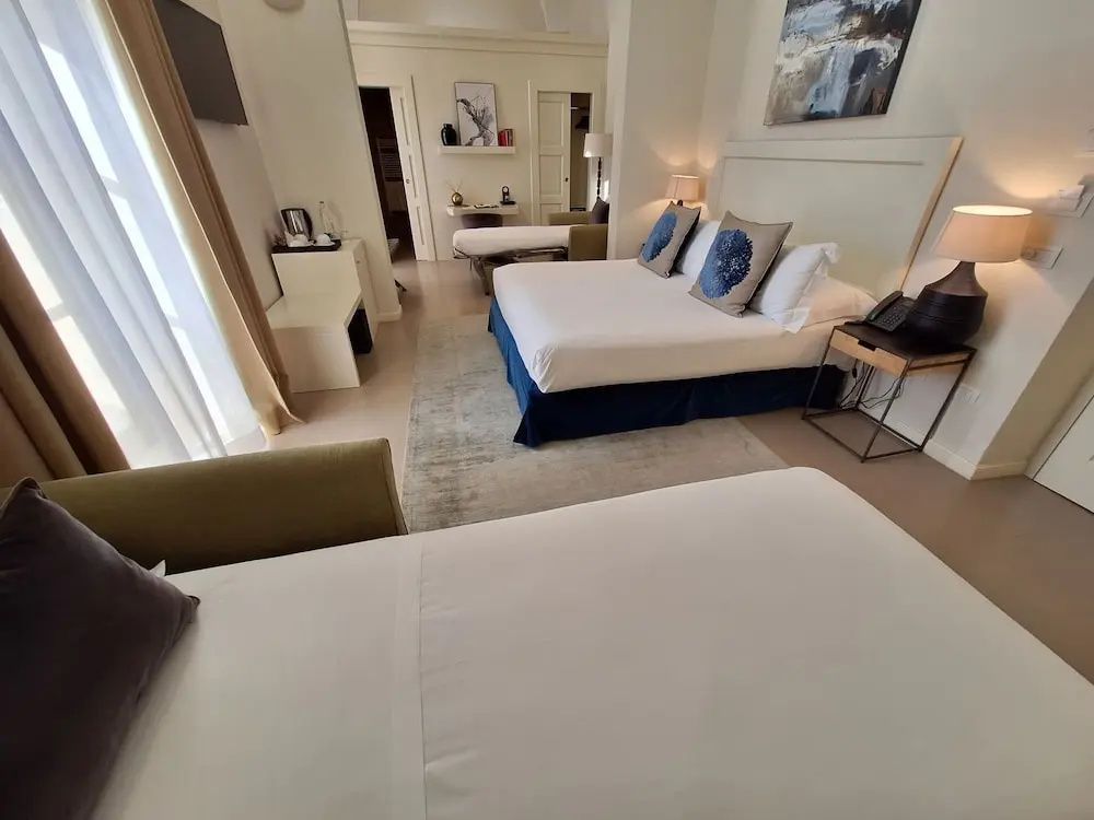 Geräumiges Hotelzimmer mit einem Doppelbett, Teppich und hellem Wandanstrich.