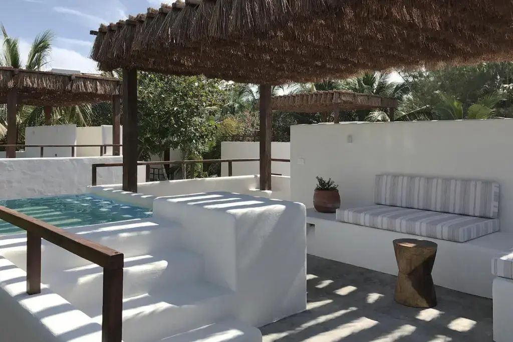 Dachterrasse mit kleinem Pool, Sonnenschutz aus Reet und weißer Sitzbank.