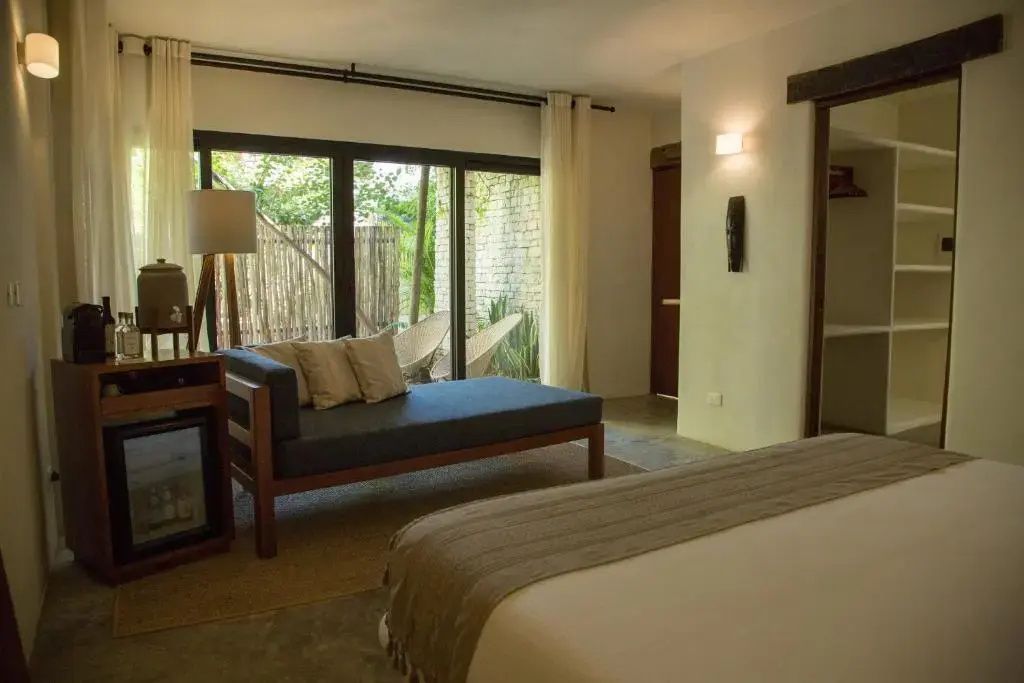 Blick durch das Hotelzimmer mit Tagesbett, Stehlampe und großer Fensterschiebetür.
