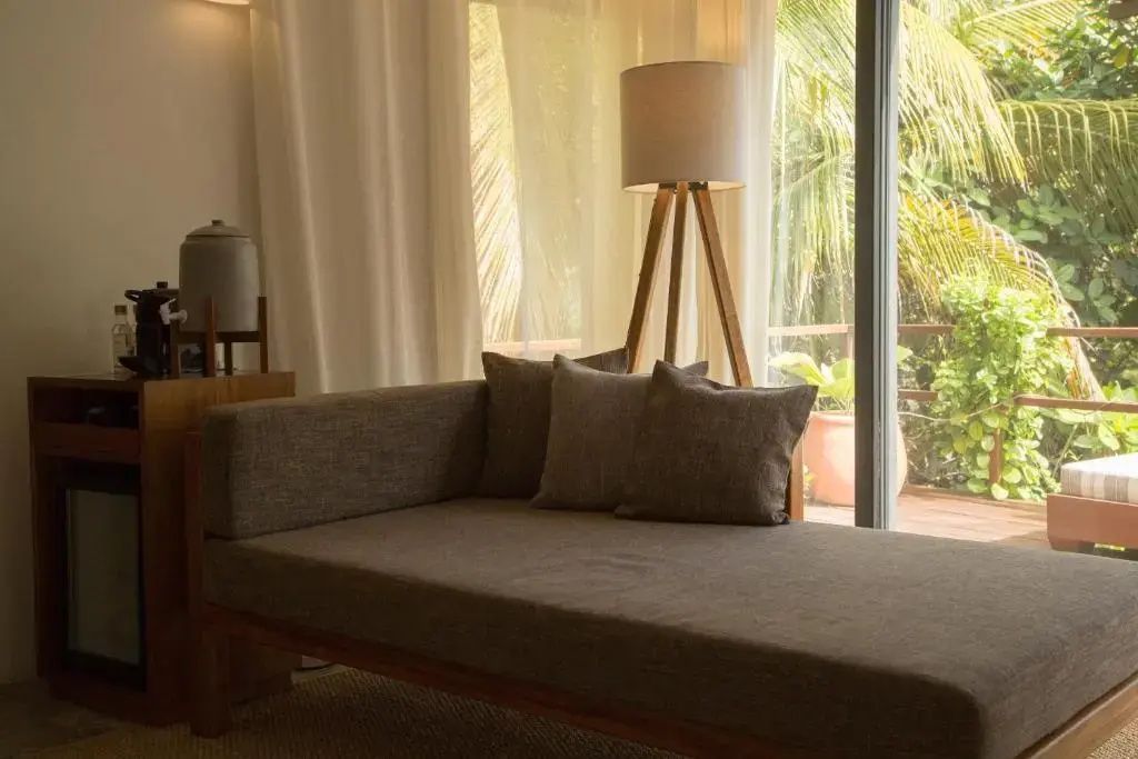 Sitzbereich im Zimmer mit beigefarbener Chaiselongue und Stehlampe aus Holz.