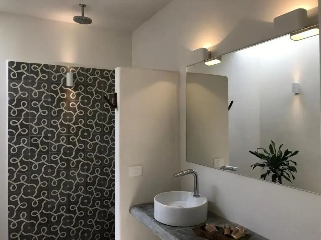 Badezimmer mit rundem Aufsatzwaschbecken, großem Spiegel und Dusche.