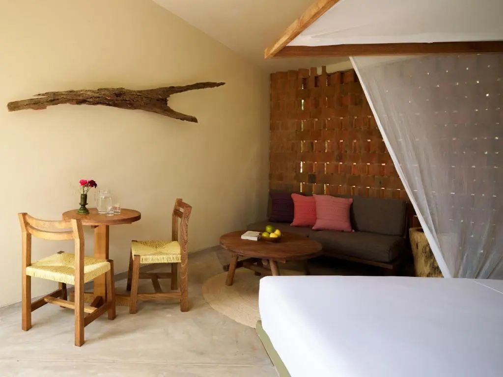 Hotelzimmer mit Holztisch, Stühlen, Sofa und einem Bett mit Baldachin.