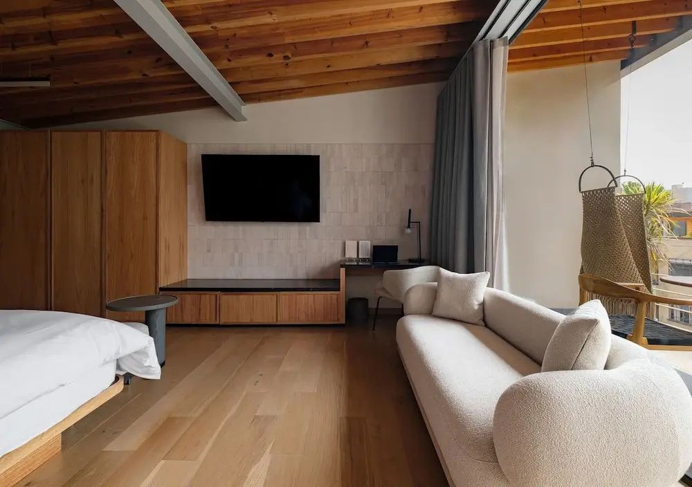 Wohnbereich mit hellem Sofa, Flachbildfernseher an der Wand und Holzboden.