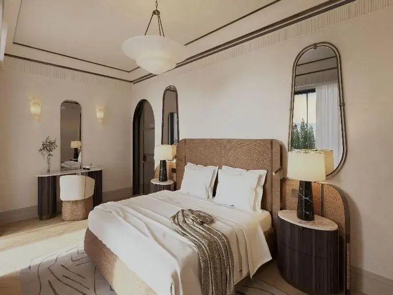 Hell eingerichtetes Hotelzimmer mit Doppelbett, Wandspiegeln und Schminktisch.