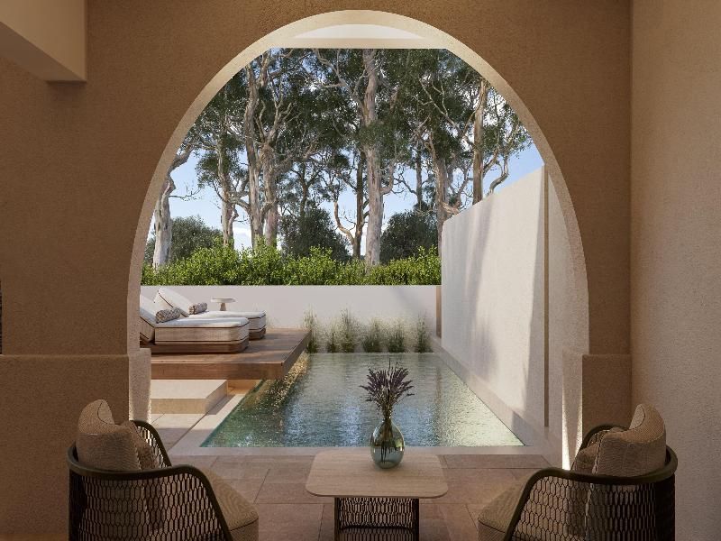 Blick durch einen Rundbogen auf eine Terrasse mit Privatpool und Sonnenliegen.