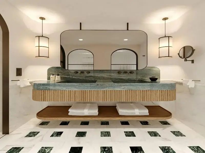 Badezimmer mit Doppelwaschtisch aus grünem Marmor und großem Wandspiegel.
