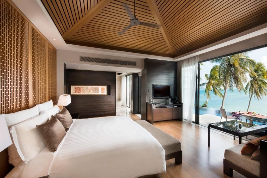 Schlafbereich mit Doppelbett, Flachbildfernseher und Blick auf den Pool und das Meer.