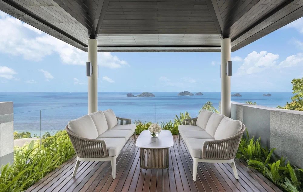 Überdachte Terrasse mit zwei Sofas und freiem Blick auf das blaue Meer und Inseln.