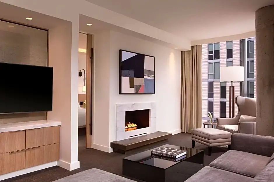 Wohnbereich einer Suite mit Kamin, Flachbildfernseher, Couch und modernem Wandbild.