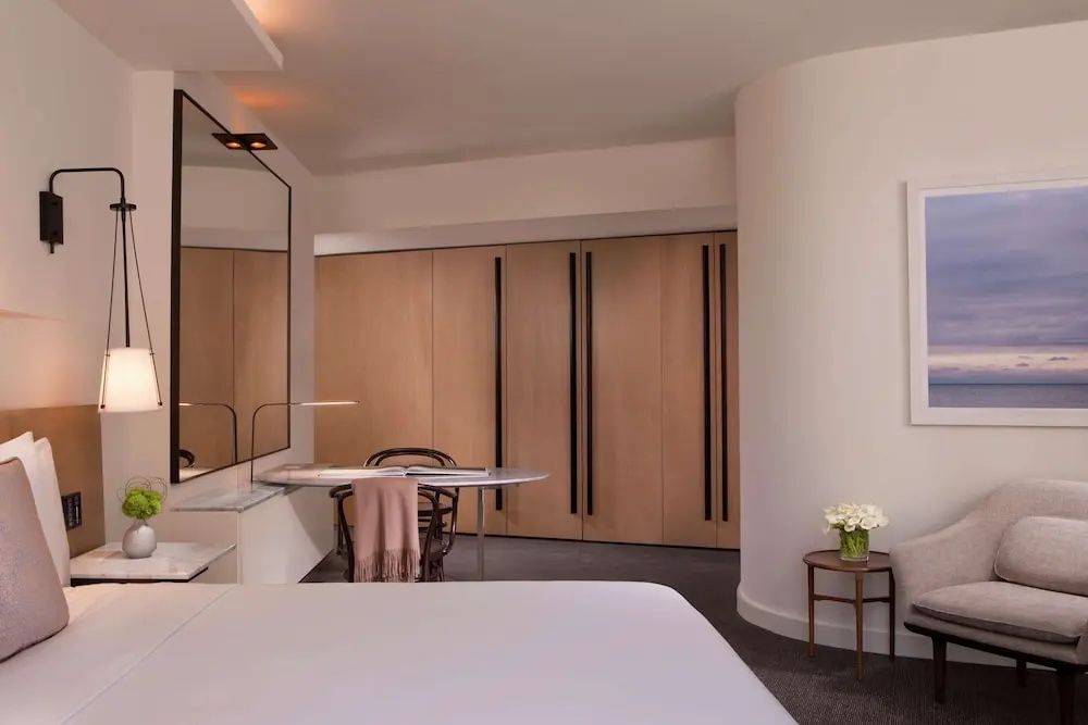 Arbeitsbereich im Hotelzimmer mit Schreibtisch, Holzschrank und hellem Wanddesign.