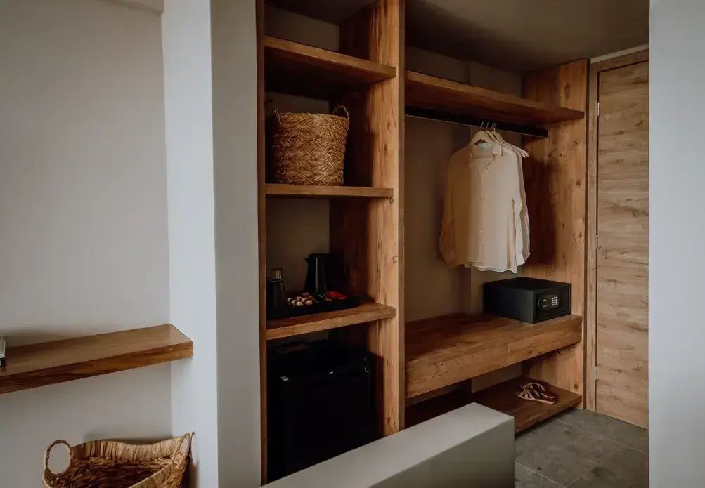 Offenes Regal aus Holz im Zimmer mit Minibar, Wasserkocher und integriertem Safe.