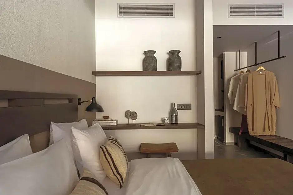 Ein Bett mit weißen Kissen und dekorative Holzregale an der hellen Wand.