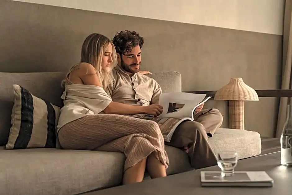Mann und Frau sitzen auf der Couch im Zimmer und schauen gemeinsam in ein Buch.