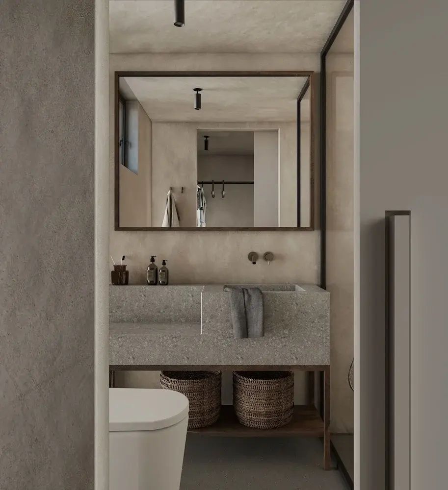Badezimmer mit rechteckigem Steinwaschtisch, Wandspiegel und Flechtkörben in hellen Tönen.