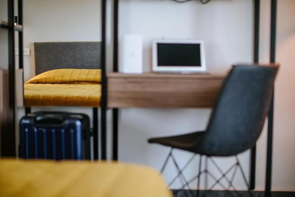 Arbeitsbereich im Hotelzimmer mit einem Laptop auf dem Schreibtisch und einem Stuhl.