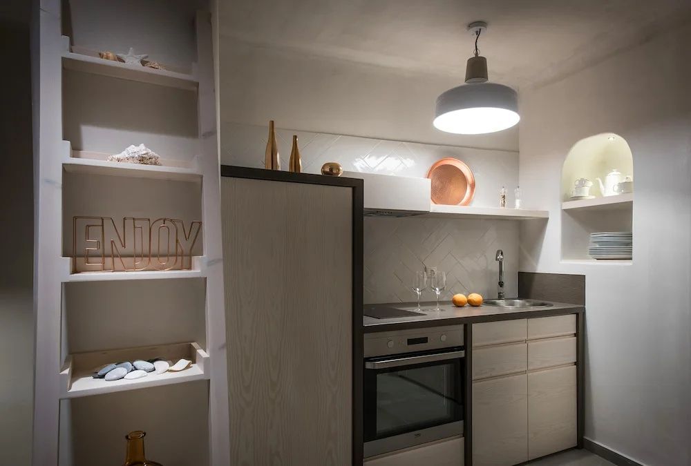 Kleine Küchenzeile in der Suite mit Herd, Backofen, Waschbecken und Wandregalen.