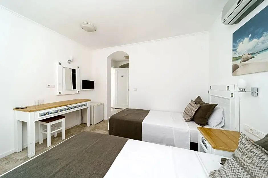 Hell eingerichtetes Hotelzimmer mit zwei Einzelbetten und einem Schminktisch.
