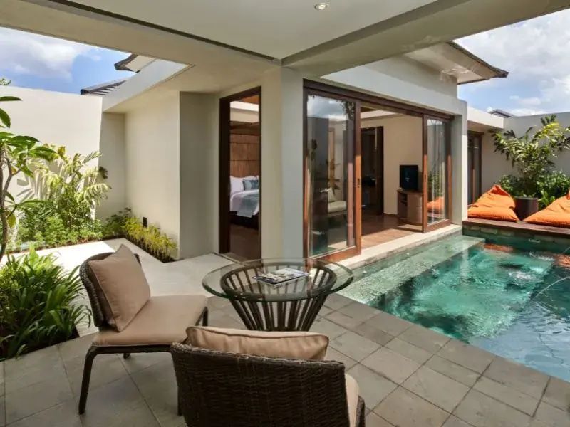 Terrasse einer Villa mit zwei Stühlen, Glastisch und angrenzendem privaten Pool.
