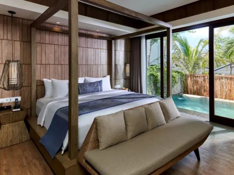 Schlafzimmer mit Baldachinbett und Glasschiebetür zum privaten Außenpool.