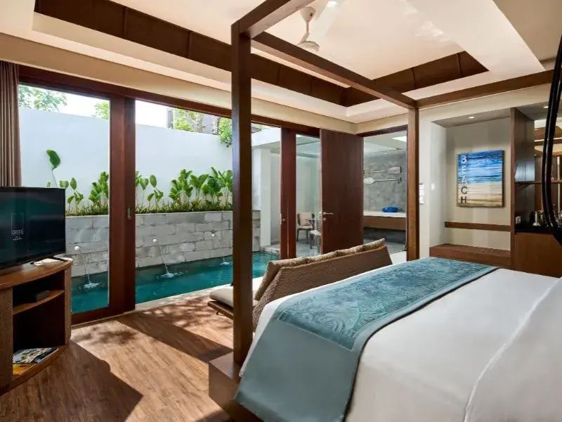 Schlafzimmer mit Holzboden und Blick durch geöffnete Glastüren auf ein Poolbecken.