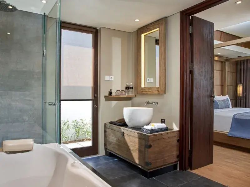 Badezimmer mit Aufsatzwaschbecken auf einer Holzkommode und beleuchtetem Spiegel.