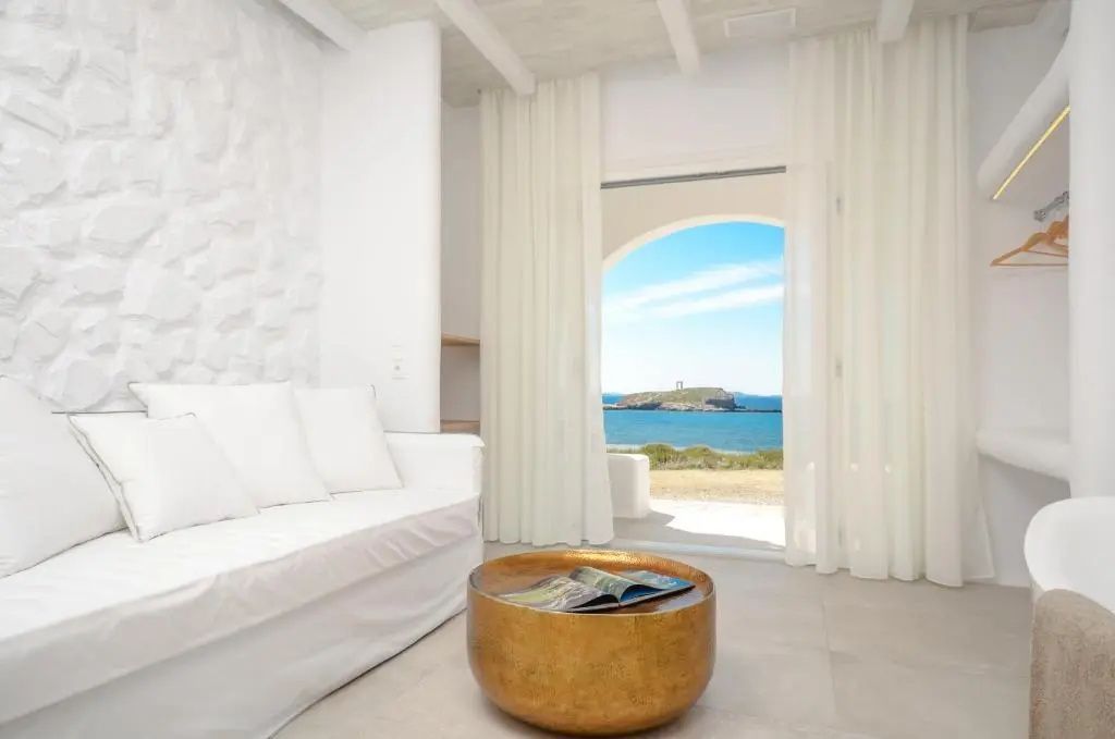 Helles Wohnzimmer mit weißem Sofa und Ausblick durch die Balkontür auf das Meer.