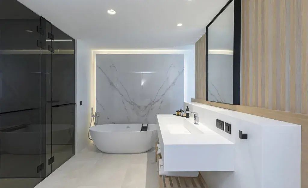 Modernes Badezimmer mit freistehender Badewanne, weißem Waschtisch und Marmorwand.